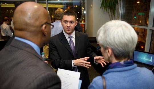Young man talking to two alumni